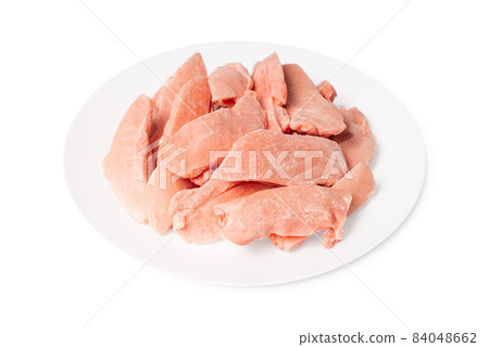 Raw frozen chicken thigh meat on a white plate on a white isolated background. 84048662
