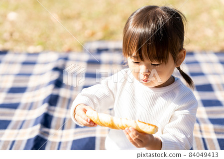 Girl eating bread on a lawn leisure sheet 84049413
