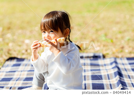 Girl eating bread on a lawn leisure sheet 84049414