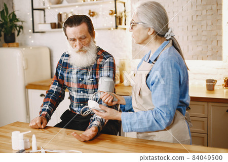 Senior woman and man at home meassure blood pressure 84049500