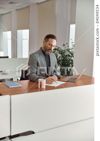Happy adult caucasian man is working in a modern office Happy adult caucasian man is working in a modern office 84049534