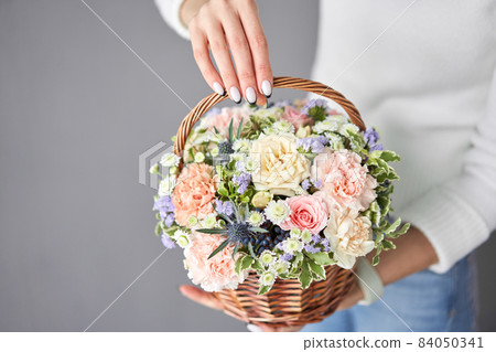 Flower arrangement in Wicker basket. Beautiful bouquet of mixed flowers in woman hand. Handsome fresh bouquet. Small flower shop and Flowers delivery. Flower arrangement in Wicker basket. Beautiful bouquet of mixed flowers in woman hand. Handsome fresh bouquet. Small flower shop and Flowers delivery. 84050341