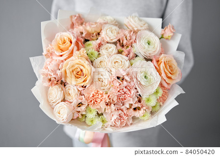 Flower arrangement in Wicker basket. Beautiful bouquet of mixed flowers in woman hand. Handsome fresh bouquet. Small flower shop and Flowers delivery. 84050420