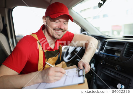 Smiling delivery service worker fill in necessary documents after shipping 84052256