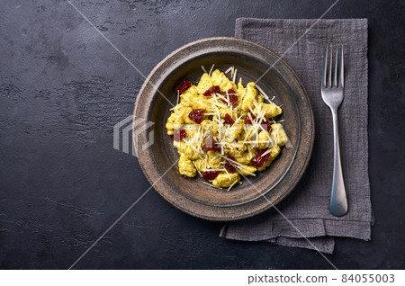 Mediterranean and Alpine potato gnocchi with parmesan and dried tomatoes in ceramic plate. Flat lay 84055003