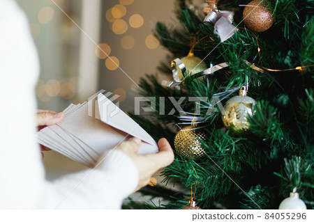 Hand holding stack of craft paper envelopes for christmas greeting card invitation design on christmas tree background with bokeh. Hand holding stack of craft paper envelopes for christmas greeting card invitation design on christmas tree background with bokeh. 84055296