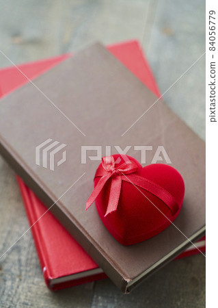 A red heart-shaped gift box placed on an antique book A red heart-shaped gift box placed on an antique book 84056779