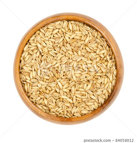 Raw hulless oats, in a wooden bowl. Seeds of Avena nuda known as naked oats. The hull separates quite readily from the grain. Small yellow grains, used in whole-food nutrition for fresh corn porridge. 84058012