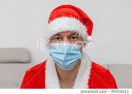 portrait man in Santa Claus hat and face mask 84058821
