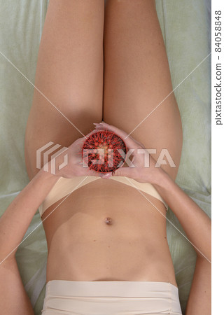 Depilation in the bikini zone concept. A woman holding a red cactus in her hand laying in light beige pants 84058848
