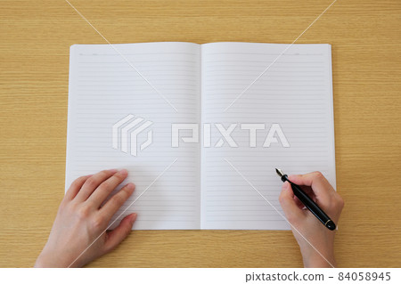 Female hand holding a double-page spread notebook and pen Blank paper Copy space Message board Background photo material 84058945