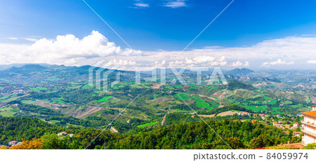 Aerial top panoramic view of landscape with valley, green hills, fields and villages of Republic San Marino 84059974