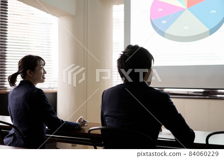 Asian business person listening to a presentation at a meeting Asian business person listening to a presentation at a meeting 84060229