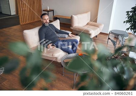 Happy adult male businessman is sitting and chilling in cozy office space 84060261