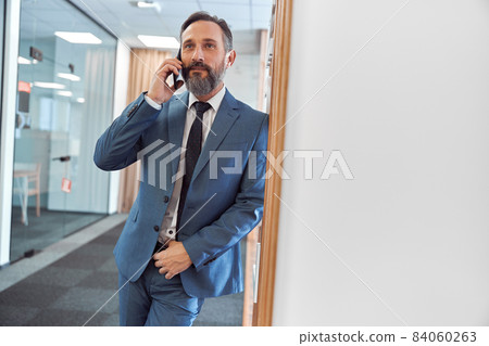 Happy adult caucasian businessman using smarthopne in a modern stylish office 84060263