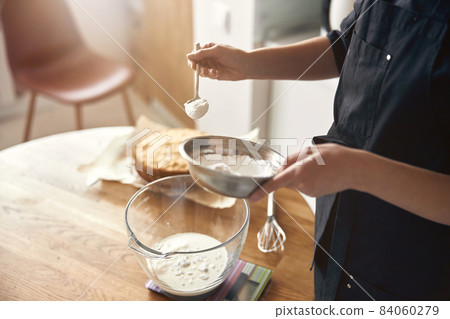 young professional female cook is preparing tasty cake at her light modern kitchen 84060279