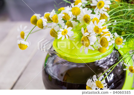 Black tea in a green cup on a wooden background and chamomile Black tea in a green cup on a wooden background and chamomile 84060385