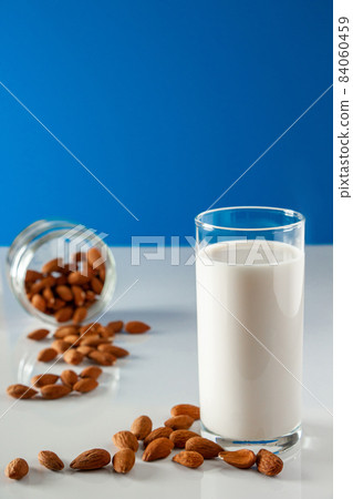 A glass of almond milk on a white background. Lactose-free vegetable diet milk. Gluten free almond drink on a blue background. Super Food - A glass of almond milk for a healthy diet. Trending food, 84060459