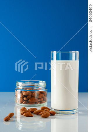A glass of almond milk on a white background. Lactose-free vegetable diet milk. Gluten free almond drink on a blue background. Super Food - A glass of almond milk for a healthy diet. Trending food, A glass of almond milk on a white background. Lactose-free vegetable diet milk. Gluten free almond drink on a blue background. Super Food - A glass of almond milk for a healthy diet. Trending food, 84060469