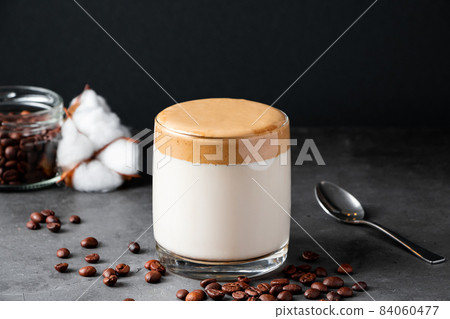 Dalgona coffee on a black background. Making a trendy drink. Fluffy sweet foam in a glass with ice milk. Dalgona coffee on a black background. Making a trendy drink. Fluffy sweet foam in a glass with ice milk. 84060477