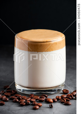 Iced dalgona coffee on a dark gray background. A glass of trendy Korean drink. Milk and sweet whipped fluffy foam. Vertical photo Iced dalgona coffee on a dark gray background. A glass of trendy Korean drink. Milk and sweet whipped fluffy foam. Vertical photo 84060478