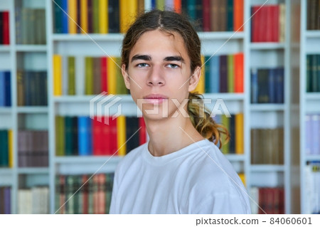 Portrait of a confident teenage boy looking at the camera in the library. 84060601