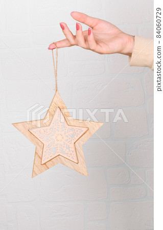 female hands holding a wooden christmas star decoration, eco wooden Christmas decor for home female hands holding a wooden christmas star decoration, eco wooden Christmas decor for home 84060729