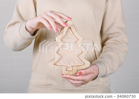 faceless woman with beige hoodie holding trendy Christmas wooden tree faceless woman with beige hoodie holding trendy Christmas wooden tree 84060730
