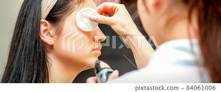 Makeup artist making professional makeup on the face of a young woman using an airbrush. 84061006