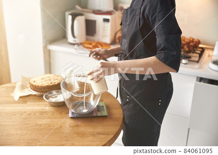 young professional female cook is preparing tasty cake at her light modern kitchen young professional female cook is preparing tasty cake at her light modern kitchen 84061095