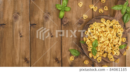 Tortellini on a wooden board with basil and parmesan. Specialties of the cuisine from Bologna and 84061185