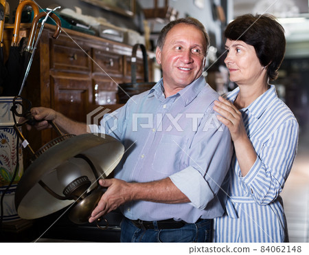 Positive adult couple looking vintage lamp in shop 84062148