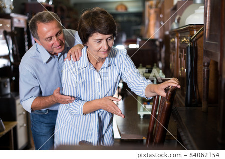 Mature couple is choosing the antique armchair Mature couple is choosing the antique armchair 84062154