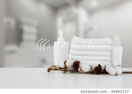 Spa still life with towels and skincare cosmetics against blurred background 84062537