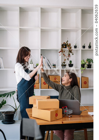 Young asian women teamwork partners packing order into box together using touchpad to do delivery to client. two female colleagues with tablet checking goods number in home office Young asian women teamwork partners packing order into box together using touchpad to do delivery to client. two female colleagues with tablet checking goods number in home office 84062639