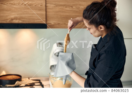 beautiful caucasian lady cook is making eclairs with help of pastry casing at home 84063025