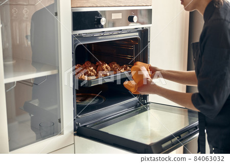 Professional confident woman is preparing custard cakes at light modern kitchen at home 84063032