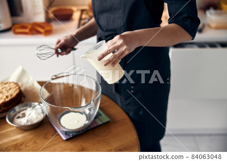 young professional female cook is preparing tasty cake at her light modern kitchen young professional female cook is preparing tasty cake at her light modern kitchen 84063048