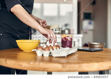 young beautiful mixed race woman is preparing marshmallow at light modern kitchen home 84063057