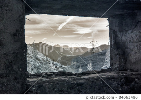 View of mountains and powerlines from the window of an abandoned stone fort  84063486