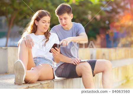 Teenagers with smartphones are siting on the step Teenagers with smartphones are siting on the step 84063560