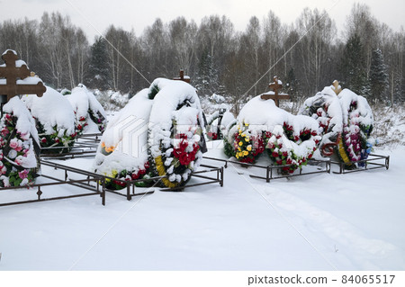 Winter cemetery. Graves with floral wreaths. A lot of snow 84065517