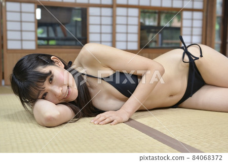A young woman in a black bikini swimsuit relaxing in a Japanese-style room in an old folk house 84068372
