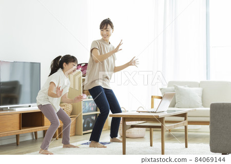 Mother and daughter dancing while watching a computer 84069144