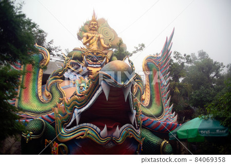 A large golden seated Buddha statue outdoors, sheltered by a 7-headed Naga in a temple of Thailand. A large golden seated Buddha statue outdoors, sheltered by a 7-headed Naga in a temple of Thailand. 84069358