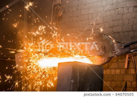 Heavy grinding equipment suspended on a chain with a hook processes and cleans cast iron reinforced concrete tubing in the workshop of an industrial plant 84070505