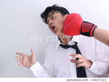 Business competition concept, businessman knocked out by getting punched in his face with red boxing gloves on white background. 84071122