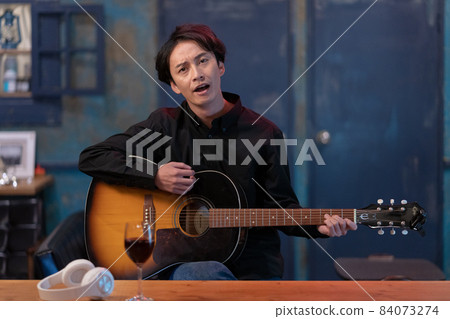 彈吉他的年輕人對著鏡頭 彈吉他的年輕人對著鏡頭 84073274