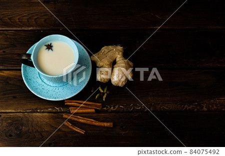 Indian masala chai tea. Masala chai spiced tea with milk and spices on dark rusty background. Indian masala chai tea. Masala chai spiced tea with milk and spices on dark rusty background. 84075492