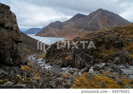 Severe northern landscape with a mountain stream in a gorge among the rocks 84076081